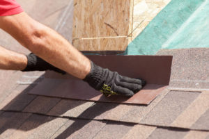 A worker installing asphalt shingles on a roof.