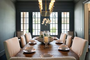 Large dining room with a large rectangular table, plush chairs, and four large windows.
