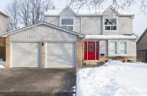 Suburban home with red door and gray siding after snowstorm